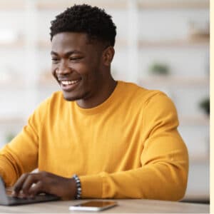 Young african-american man smiling while on laptop